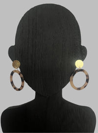 Earrings on a black mannequin head against a plain background
